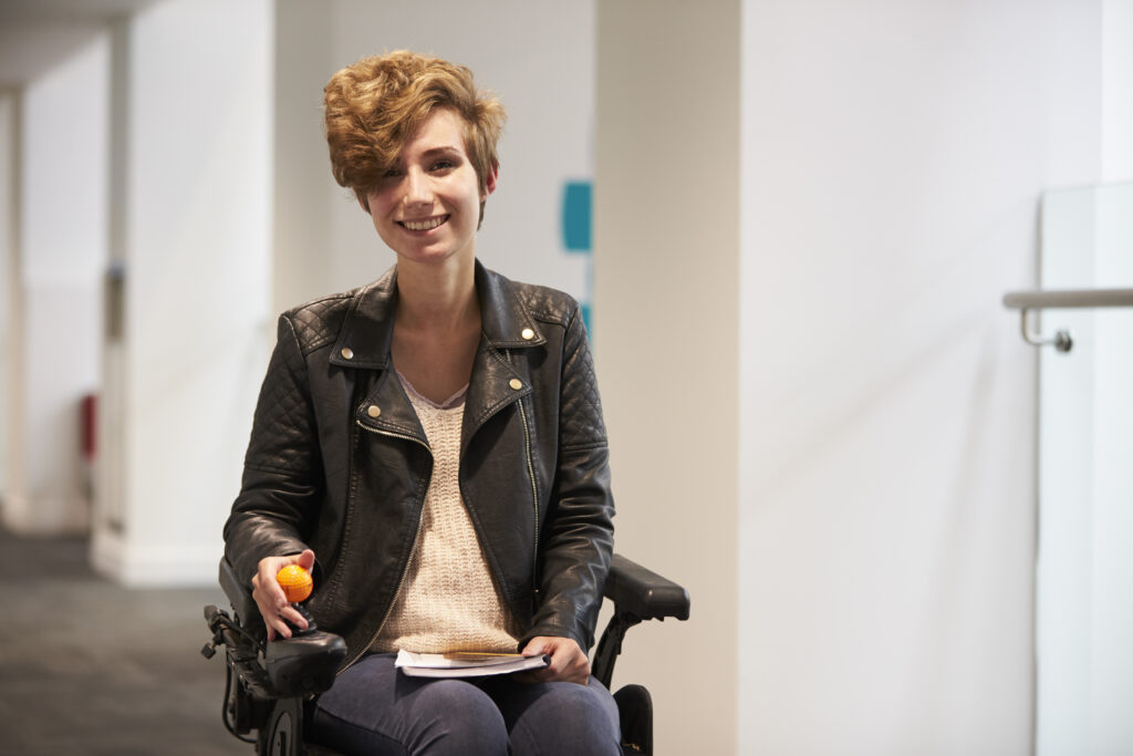 Wheelchair user smiling holding a ball and a book